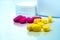 Pile of yellow and pink tablets pills on blurred background of plastic pills bottle with copy space. Ibuprofen for relief pain.