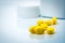 Pile of yellow tablets pills on blurred background of plastic pills bottle with copy space. Ibuprofen for relief pain, headache