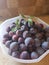 Piled purple plum fruits in a large bowl in aa kitchen