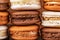 Piles of brown and white french macarons or macaroons, chocolate, coffee, salted caramel and vanilla
