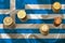 Piles of coins of the European Union currency against the background of the flag of the country of Greece, financial concept,