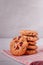 Piles of delicious chocolate chip cookies on a white plate with a milk bottle. Pastry utensils with white linen napkins on a woode