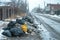 Piles of garbage in black bags are strewn along the road on a slushy winter day