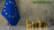 Piles of gold coins on a marble table against the background of the flag of he European Union.