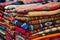 piles of handwoven, traditional patterned rugs in a marketplace