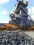 Piles of raw steel briquettes. Heap of coal anthracite in the port. Port cranes for coal loading