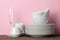 Piles of white ceramic tableware, plates, saucers, cups on a pink background. kitchenware