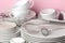 Piles of white ceramic tableware, plates, saucers, cups on a pink background. kitchenware