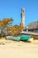 Pilgrim Monument in Provincetown Cape Cod USA jutting into sky beside weathered buildings and boats pulled up on the beach