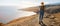 Pilgrim on the pilgrimage. young woman walking ocean coastal trail. banner with copy space