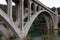 Pilings and arches of the Rogue River bridge in Gold Beach, Oregon at sunset reflected in water