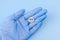 A pill with a crazy smiley in a hand in a medical glove on a blue background. Drug concept
