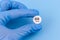 A pill with a crazy smiley in a hand in a medical glove on a blue background. Drug concept
