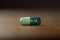 A pill with the text covid-19 printed on it on a wooden table