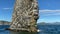 Pillar-shaped rock protruding from the water with the nests of many seagulls.