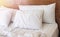 Pillows on the bed with white bedlinen and wooden bedhead