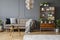 Pillows and blanket on beige couch in grey living room interior