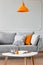 Pillows on a couch, orange lamp and coffee table in a living room interior. Real photo