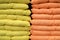 Pillows are stacked on shelf. Pillows background. Soft comfortable orange and yellow Household items for home bedroom, bed