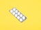 Pills in a gray package. A single pack of white pills and tablets. Medicinal drugs on a colorful yellow background.