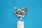 Pills heart out of pill bottle on blue background, top view