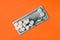 The pills are on a hundred dollar bill. Orange background, close-up. Concept for buying medicines, cost of treatment, medicine