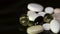 Pills spinning. Pile of several medicines. White tablets with pills on black background. Opened medicine capsule pill