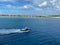 A pilot boat escorting a cruise ship into the Aruba port with a view of the coastline