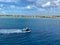 A pilot boat escorting a cruise ship into the Aruba port with a view of the coastline