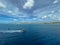 A pilot boat escorting a cruise ship into the Aruba port with a view of the coastline