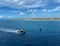 A pilot boat escorting a cruise ship into the Aruba port with a view of the coastline