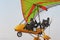 The pilot flies on a yellow motor hang-glider