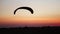 The pilot on the paraglider comes to land in the field at sunset