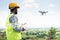 Pilot with safety hardhat flying drone using remote controller - Concept of engineer doing aerial survey or inspection using UAV