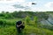 The pilot of an unmanned aerial vehicle holds a drone control panel in his hands. Flying a quadrocopter over an old abandoned