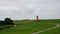 Pilsum lighthouse in a green grassy field with a cloudy sky in the background