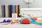 Pin cushion, brightly colored strips of fabric, sewing accessories  on the background of stack of fabrics and sewing machine