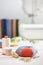 Pin cushion, brightly colored strips of fabric, sewing accessories  on the background of stack of fabrics and sewing machine