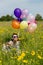 Pin up Girl on a flowery meadow with colorful balloons