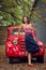 Pin-up girl posing on a red russian retro car background. A playful interested look is cast aside.