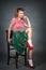 Pin-up girl sitting on a chair on a grey background dressed in a red blouse and green skirt on the feet white socks and red shoes