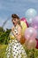 Pin up Girl with a suicide roll standing on the meadow with colorful balloons