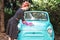 Pin-up girl in vintage clothes is washing mint old car.