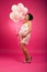 Pin Up retro studio shot of a pregnant woman with balloons. Photo taken in the studio on a pink, bright background