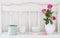 Pinc roses in vase and dinnerware on wooden shelf