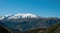Pindus mountain range Greece. Snowy peak of Pindos misty mountain, forest, blue sky background