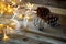 Pine cones next to gold garland lights on wooden background