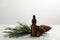 Pine essential oil, cones and branch on white marble table