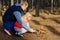 In the pine forest father and daughter feed a squirrel nuts.