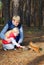 In the pine forest father and daughter feed a squirrel nuts.